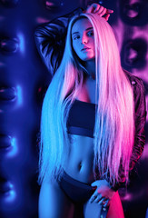 Wall Mural - beautiful stylish fashionable girl in bodysuit posing in photo Studio on dark background in neon light