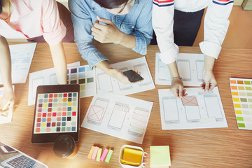Wall Mural - mobile apps developers team designing, discussing together on a ui/ux wireframe screens layout. ui/u