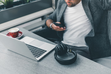 Young beard man using laptop on office, freelance work, outdoor close up hipster portrait, brutal, guy listening music on earphones, make photo and video, production, Bali, watch OS