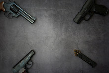 Firearms Laid Out Along The Line. Three Guns Pistols, Cartridges Close-up On A Gray Concrete Background. Copy Space