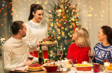 Wall Mural - holidays and celebration concept - happy friends having christmas dinner at home