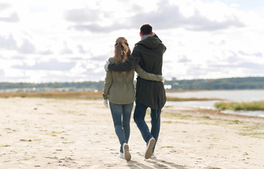 Poster - love, relationship and people concept - smiling couple walking along autumn beach and hugging