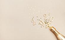 Creative Christmas And New Year Composition With Golden Champagne Bottle, Confetti Stars And 2020 Numbers. Flat Lay.