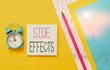 © Zofia - Conceptual hand writing showing Side Effects. Concept meaning secondary undesirable effect of a drug or medical treatment Notepads marker colored paper sheets alarm clock wooden background