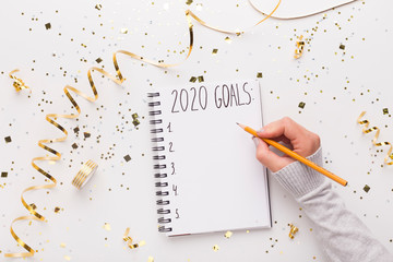 Wall Mural - Woman writing down in notepad with 2020 goals