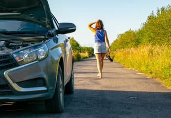 Wall Mural - Beautiful young girl, in despair, she can not continue her journey because of the fact that her car broke down.