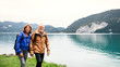 © Halfpoint - A senior pensioner couple hiking by lake in nature, holding hands.