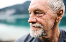 A Close-up Portrait Of Senior Man Pensioner Standing Outdoors In Nature.