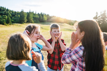 group of school children standing on field trip in nature, playing.