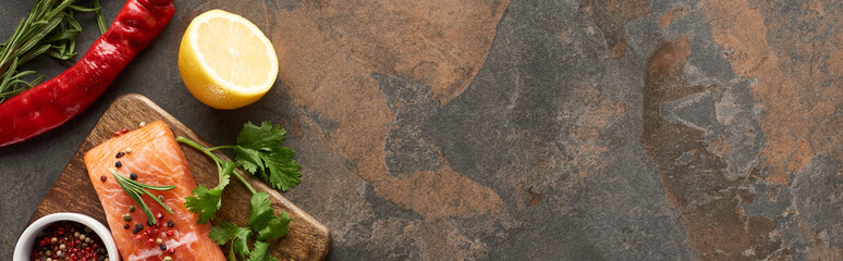 Wall Mural - top view of raw salmon with peppercorns, parsley on wooden cutting board near lemon and chili pepper, panoramic shot