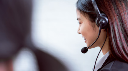 Back view of woman consultant wearing microphone headset of customer support phone operator at workplace.