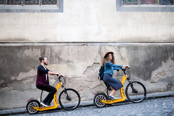 Wall Mural - young tourist couple travellers with electric scooters in small town.