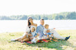 © Sunshine - Close-knit family with young children sitting on a blanket on the lake