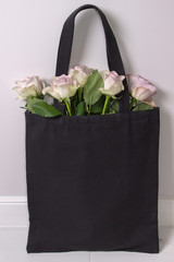 Wall Mural - Black cotton tote bag with light violet roses inside. Styled photography