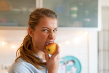 Portrait Of Young Woman Eating An Apple At Home