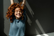 © Westend61 - Portrait of happy redheaded woman with eyes closed raising hands