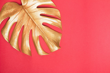 Wall Mural - Gold monstera leaf on red background