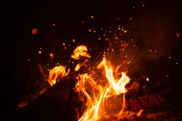 Beautiful abstract background on the theme of fire, light and life. Burning red hot sparks fly from large fire in the night sky. Burning embers glowing flying over black background.