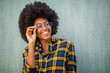 © mimagephotos - Close up young afro woman holding glasses and smiling against green background