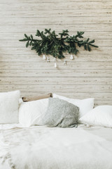 Christmas / New Year composition. Scandinavian bed room with white linen with christmas decorations made of fir branches and white toys. Winter holidays concept.