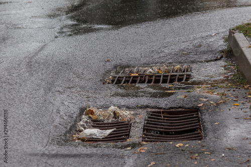 Flow of water during heavy rain and clogging of street sewage. The flow of water during a strong hurricane in storm sewers. Sewage storm system along the road to drain rain into the drainage system