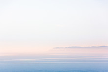 Minimalist Landscape Scene Of Sandwich Bay, Kent On A Misty But Bright Summer Morning. The Town Of Deal Peninsular Can Just Be Seen Through The Mist And There Is A Soft Glow Of Sunrise.