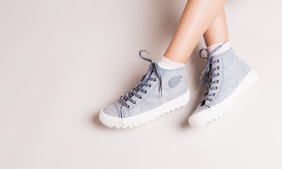 Wall Mural - Pastel blue sneakers on crossed legs - casual footwear