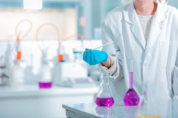 Wall Mural - young medical technologist female making testing with test tube while doing research in science labo