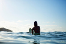 Silhouette Female Surfer Straddling Surfboard, Waiting In Sunny Blue Ocean