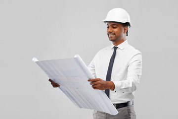 architecture, construction business and people concept - smiling indian male architect in helmet with blueprint over grey background