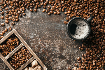 Coffee cup and coffee beans on dark stone background. Top view with copy space. Background with free text space.