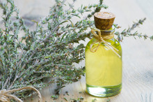 Glass Bottle Of Thyme Essential Oil And Bunch Of Dry Thyme On Wooden Rustic Background. Dried Spice Zahter Thyme And Oil Concept