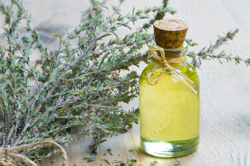 Fotografía glass bottle of thyme essential oil and bunch of dry thyme on wooden rustic background