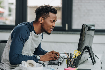 attentive african american programmer working on computer in office