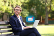 © Pixel-Shot - Handsome young businessman with laptop resting on bench in park