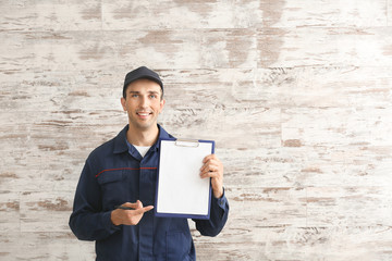 Wall Mural - Male car mechanic with clipboard on wooden background