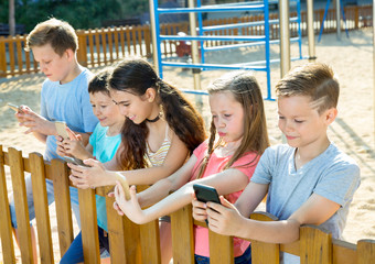 Wall Mural - Five children sitting and playing in smartphone