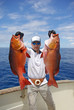 © sablin - deep sea fishing, man holding two red snapper. Boat fishing, big game