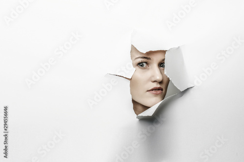 Fotomural Woman looking out from a hole of torn paper