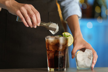 Woman preparing fresh alcoholic cocktail with lemon and mint at bar counter, closeup