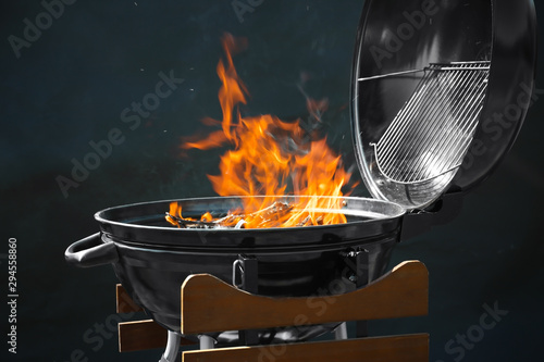 Fotografía New modern barbecue grill with burning firewood on dark background