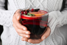 Woman holding glass cup of tasty mulled wine, closeup