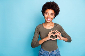 Poster - Photo of casual cute lovely sweet nice girlish feminine millennial woman wearing jeans denim green sweater smiling toothily showing you heart sign isolated over vibrant blue color background