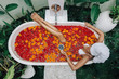 © Alena Ozerova - Woman relaxing in outdoor bath with flowers in Bali spa hotel.