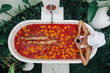 © Alena Ozerova - Woman relaxing in outdoor bath with flowers in Bali spa hotel.