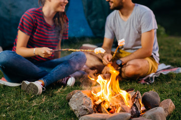 Wall Mural - closeup of friends barbecuing marshmallows on camping fire