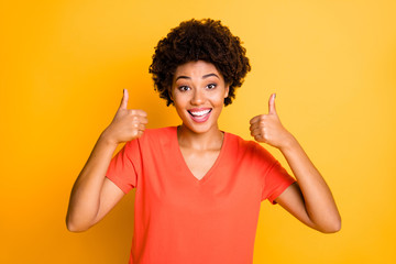 Canvas Print - Photo of charming cute cheerful black afro americal lady smiling toothily wearing t-shirt showing you double thumb up while isolated with yellow vibrant color background