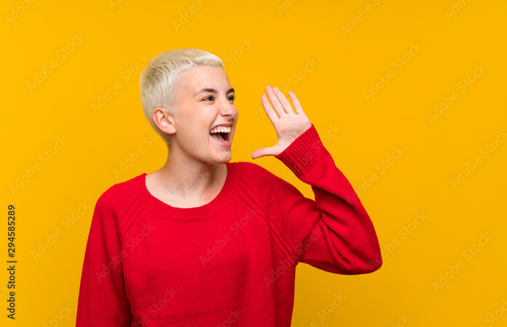 Teenager girl with white short hair over yellow wall shouting with mouth wide open - obrazy, fototapety, plakaty 