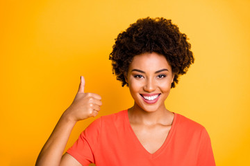 Canvas Print - Photo of cheerful cute charming girlfriend thumbing up to show perfect quality of something isolated over yellow vivid color background