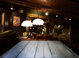 Blurred cafe restaurant club background with wooden table. Place under the text. Empty place. Interer cafe.